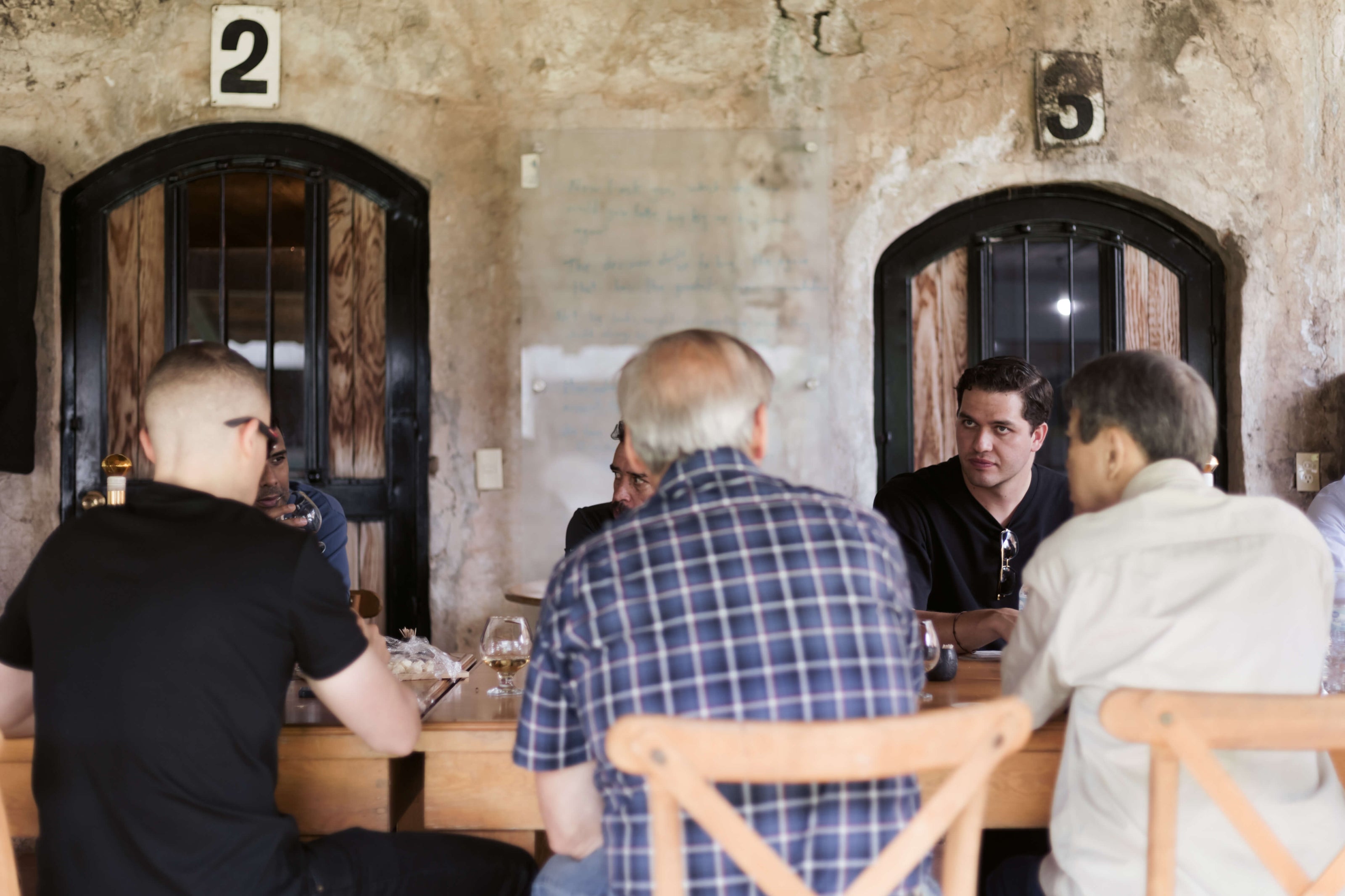 People sitting at a table in a rustic setting with stone walls and wooden doors.